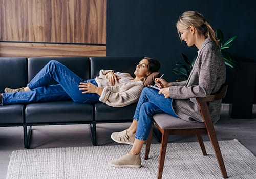 Person lying down on couch and talking to their therapist about addiction treatment programs