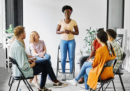 People sitting in a circle with someone standing up to share at an intensive outpatient program